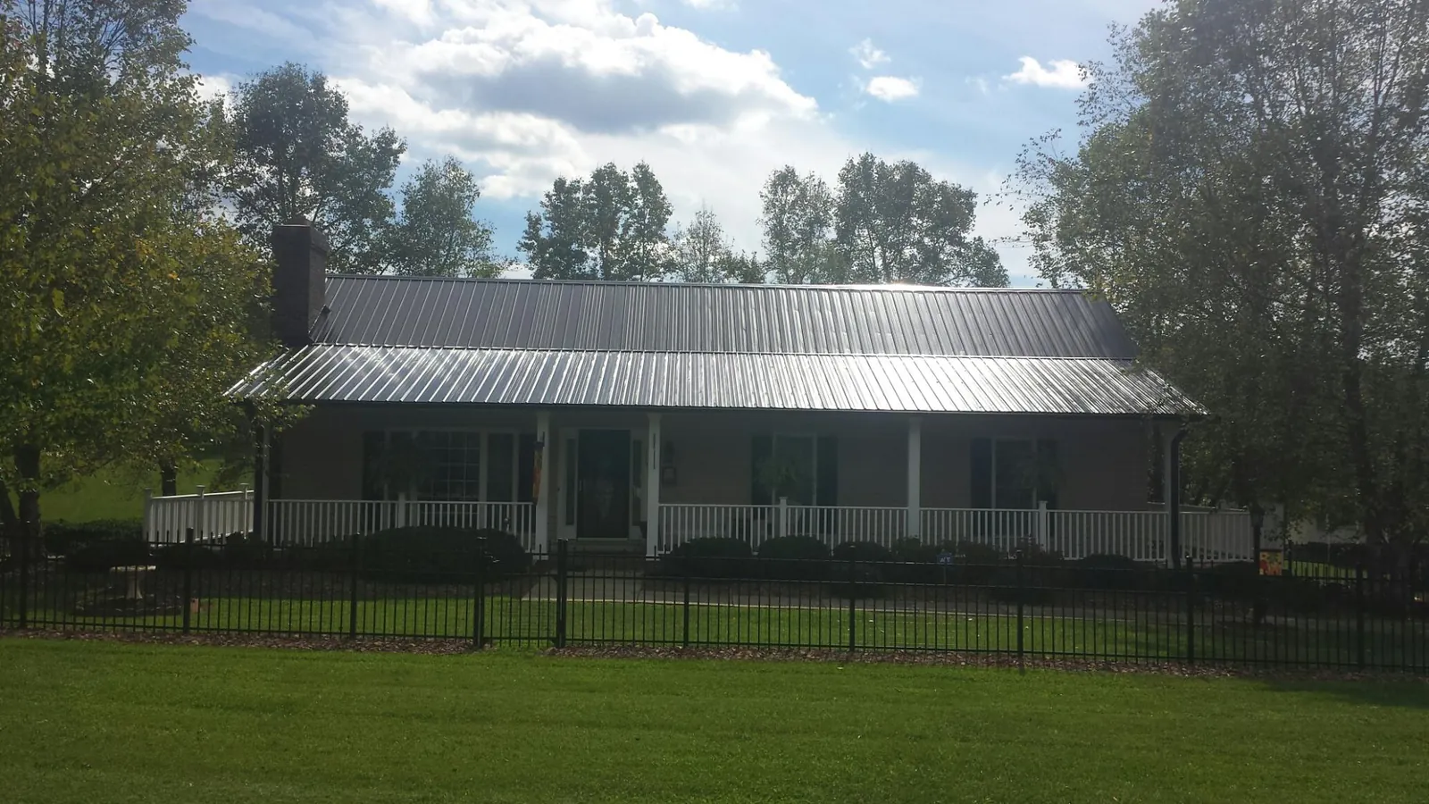 Gray metal roof on a brick ranch with a full width front porch — Gutter Guard Installation work by our crew in Philipsburg