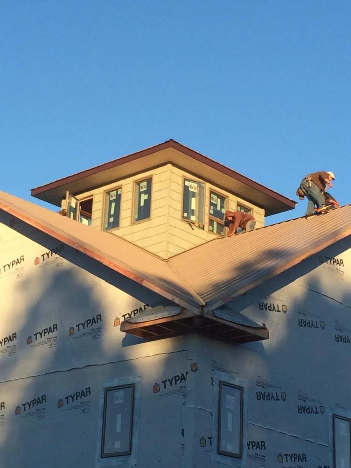 Roofers working around a rooftop cupola on a new metal roof at sunset — Roof Waterproofing in Philipsburg by Roofing Brothers